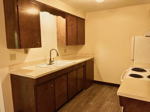 A kitchen with brown cabinets and a white sink.