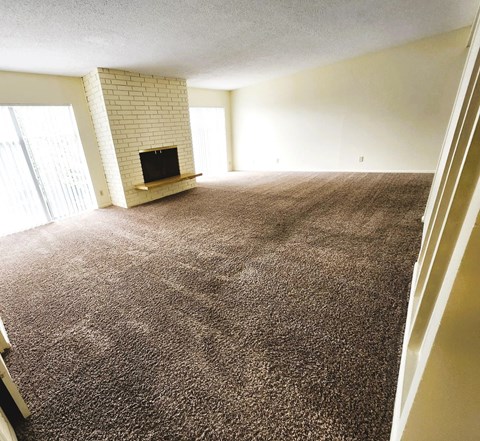 A living room with a fireplace and carpeted floor.