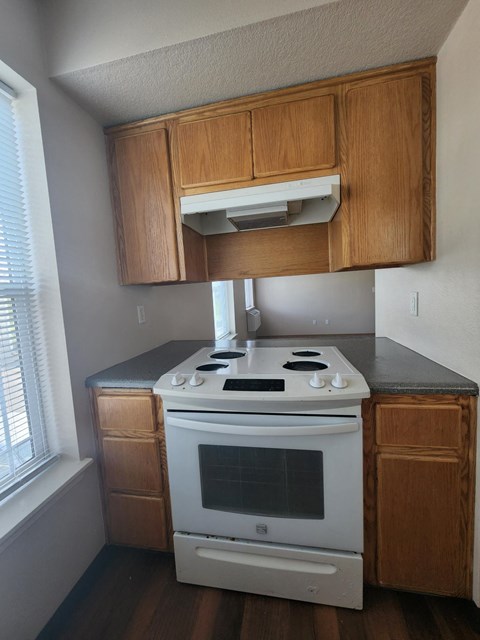 A white stove and oven in a kitchen with wooden cabinets.
