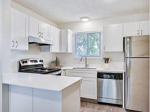 a white kitchen with stainless steel appliances and white cabinets
