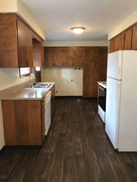 A kitchen with white appliances and wooden cabinets.
