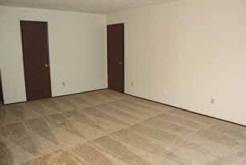 an empty living room with white walls and two doors