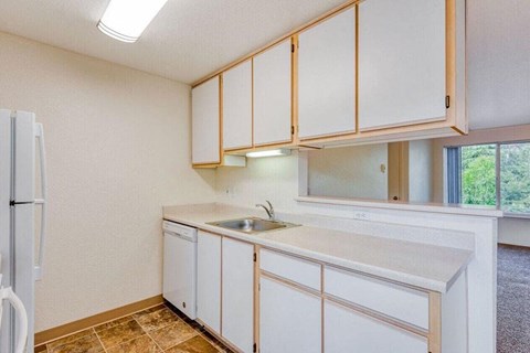 A kitchen with white cabinets and a refrigerator.