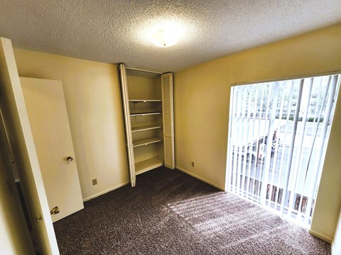A room with a carpeted floor and a window with blinds.