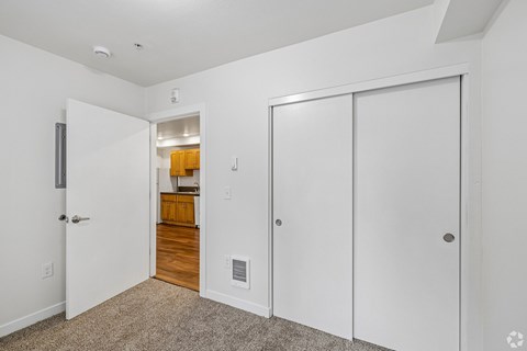 A white door is on the left of a hallway with a carpeted floor.