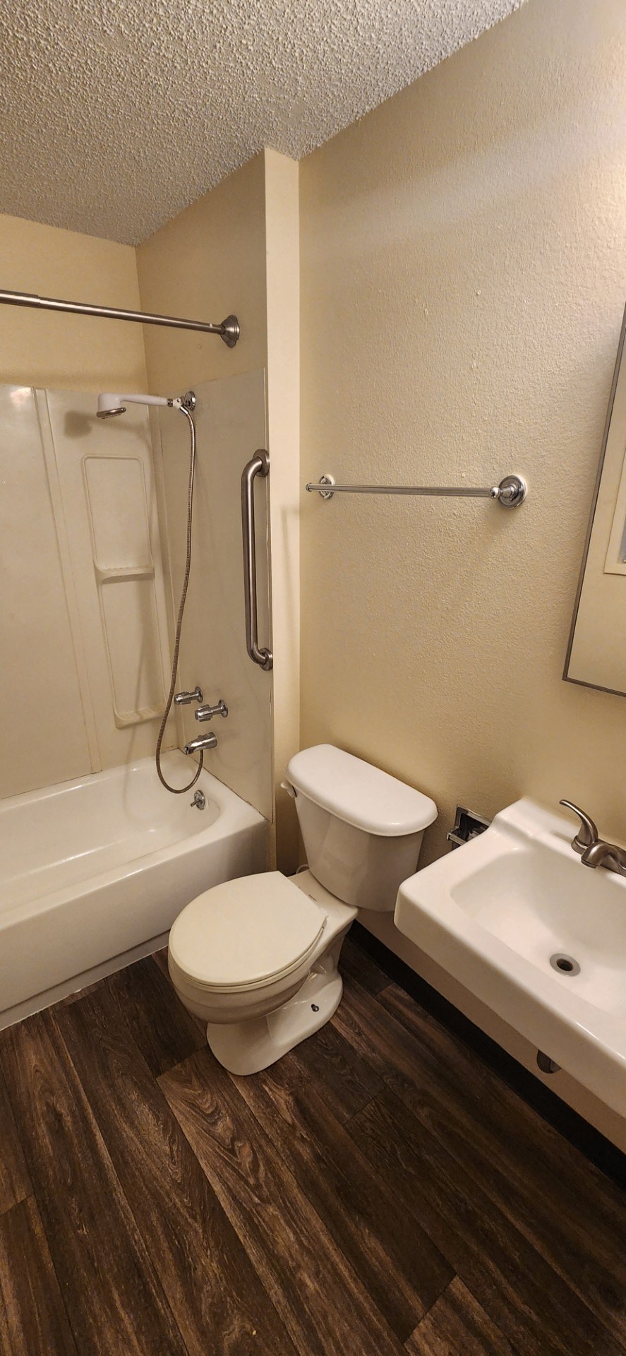 Nell Anna Court white toilet sits in a bathroom with a wooden floor and a white sink.