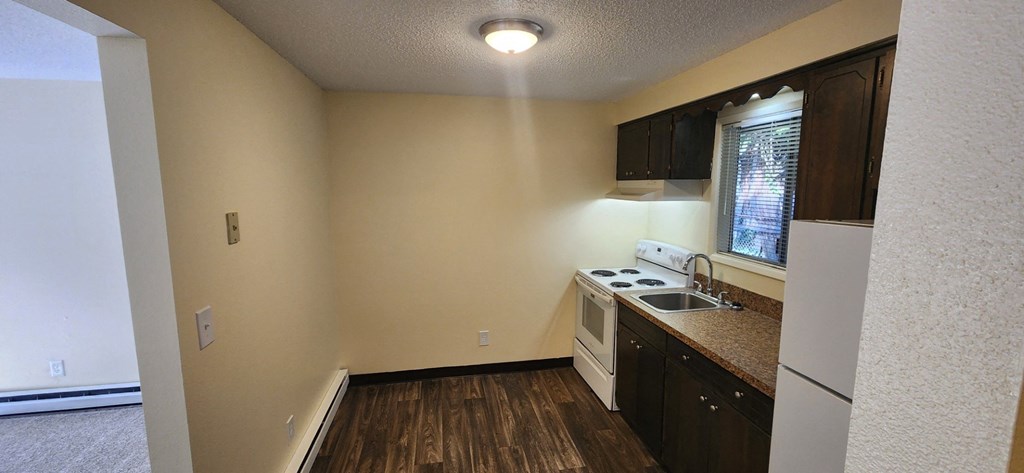 Nell Anna Court small kitchen with white appliances and wooden floors.