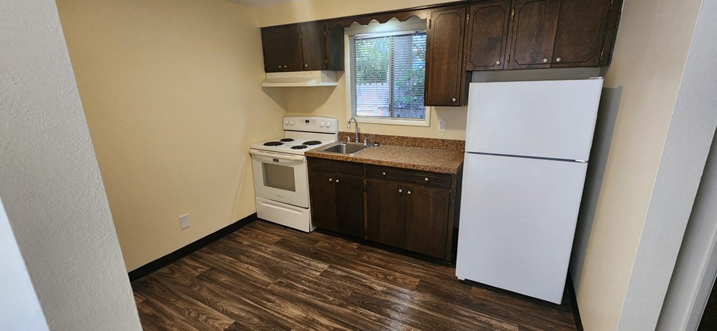 Nell Anna Court small kitchen with a white fridge and white stove.