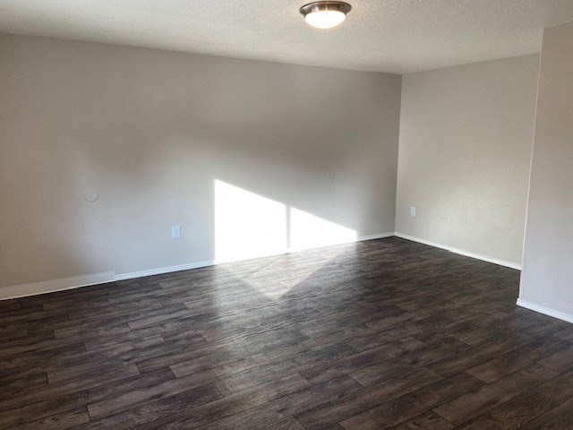 A room with wooden flooring and a window letting in sunlight.
