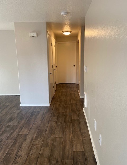 A long hallway with wood floors and white walls.