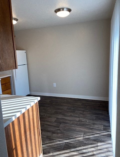 A kitchen with a white refrigerator and wooden cabinets.