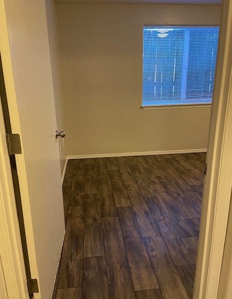 A room with a wooden floor and a window with blinds.