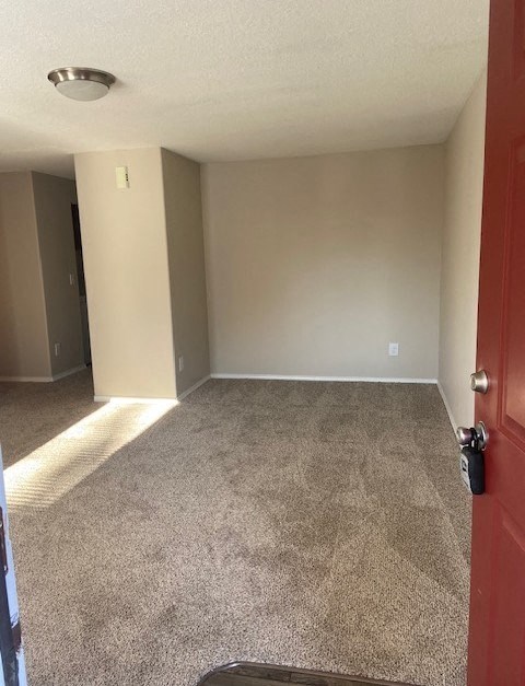 A room with a red door and carpeted floor.
