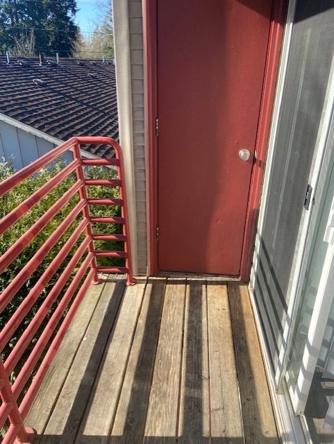 A red door is open to a wooden deck.