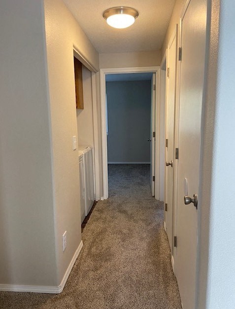 A long hallway with a carpeted floor and white walls.