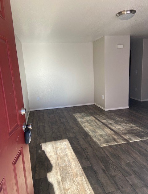 A room with a red door and a wooden floor.