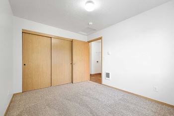 A room with a carpeted floor and a white wall with a switchboard.