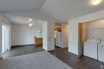 A spacious living room with a grey rug in the center.