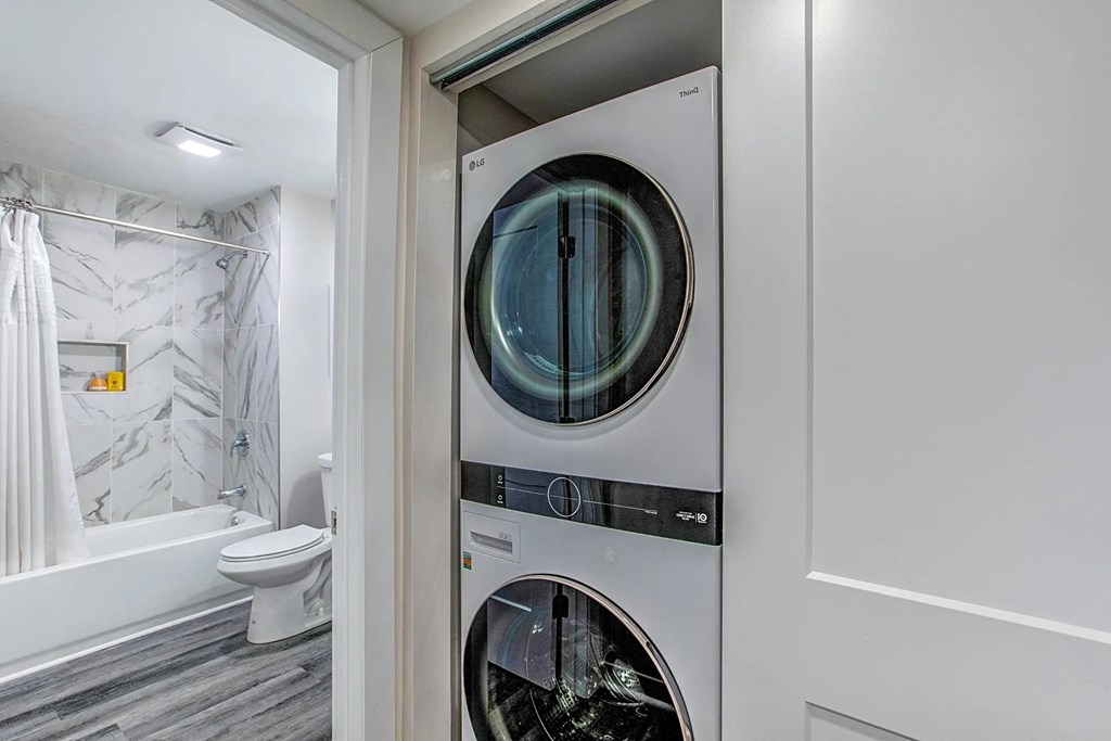 a small laundry room with a washer and dryer next to a bathroom