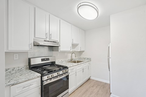 A kitchen with white cabinets and a stove top oven.