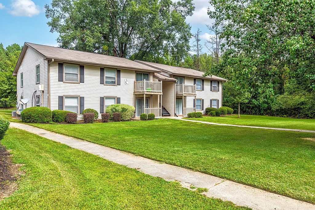a white house with a green lawn and sidewalk