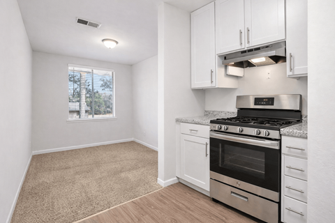A kitchen with white cabinets and a stove top oven.