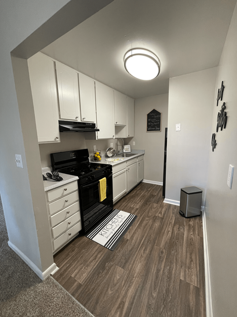 A kitchen with a black stove top oven and white cabinets.