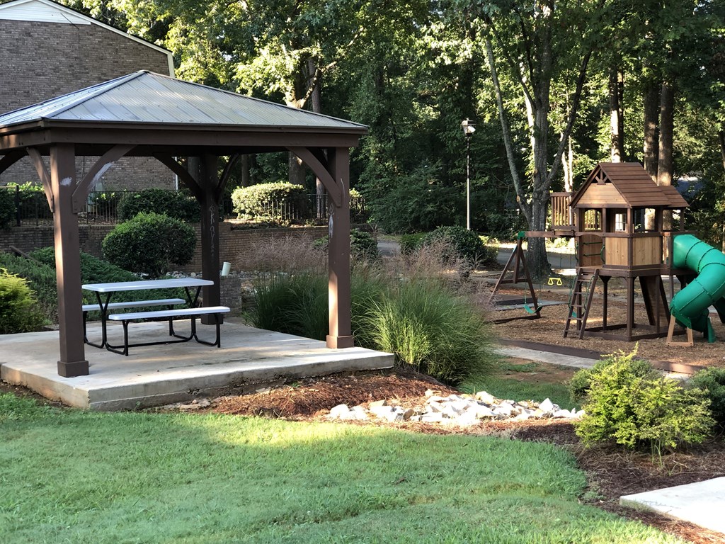 a gazebo in a park with a playground in the background