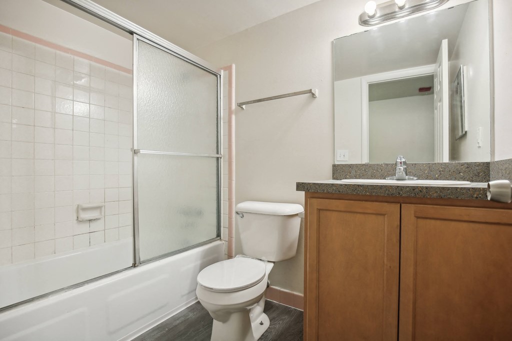 A white toilet sits in a bathroom next to a glass shower door.
