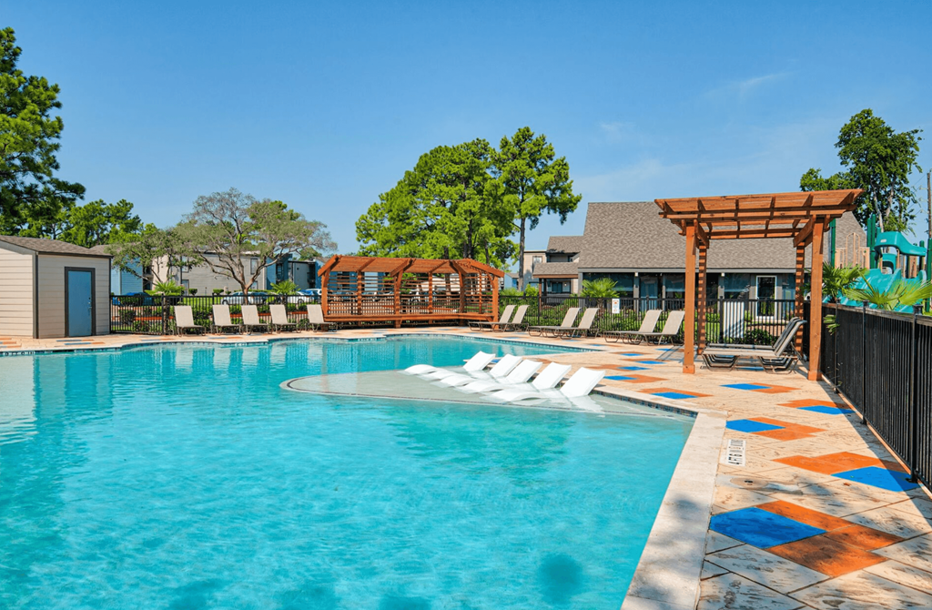 A pool with a wooden pergola and lounge chairs.