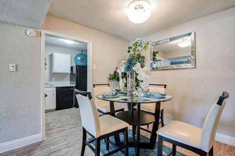 A dining room with a table set for two and a mirror above it.