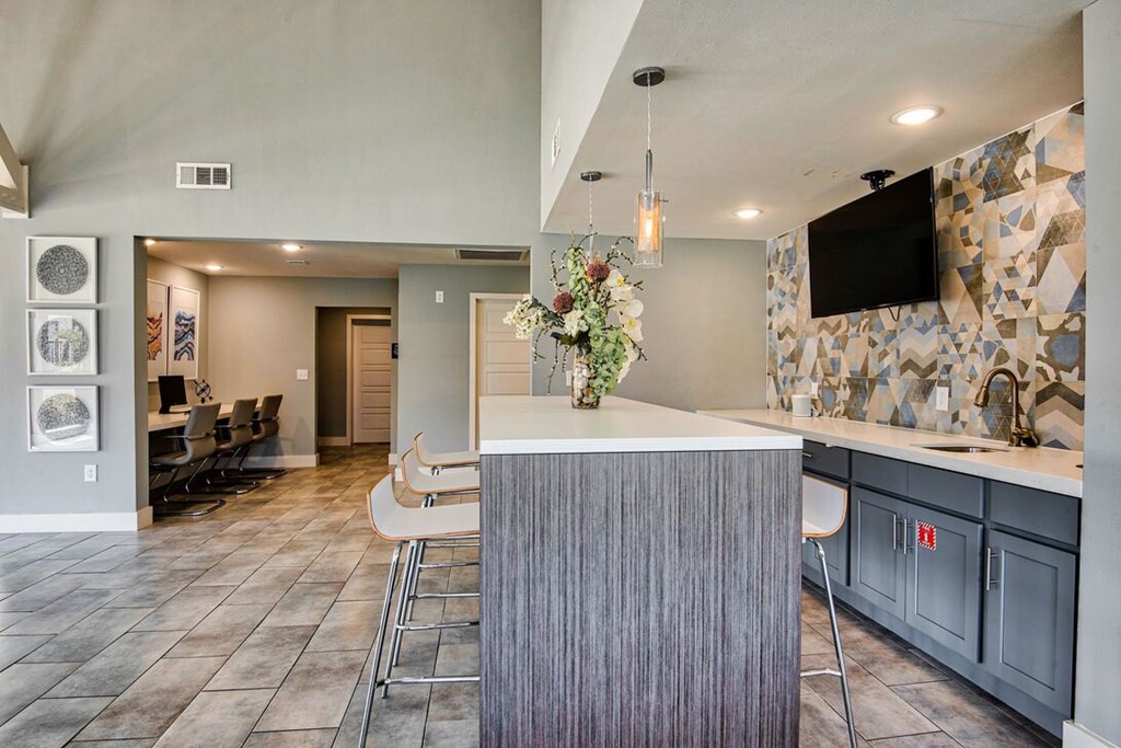 A modern kitchen with a bar area and a television mounted on the wall.