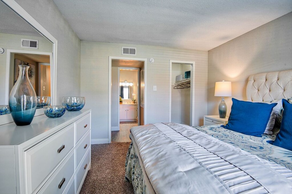 A bedroom with a large bed and a dresser with vases on top.