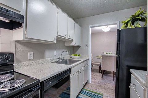 A kitchen with white cabinets and a black refrigerator.