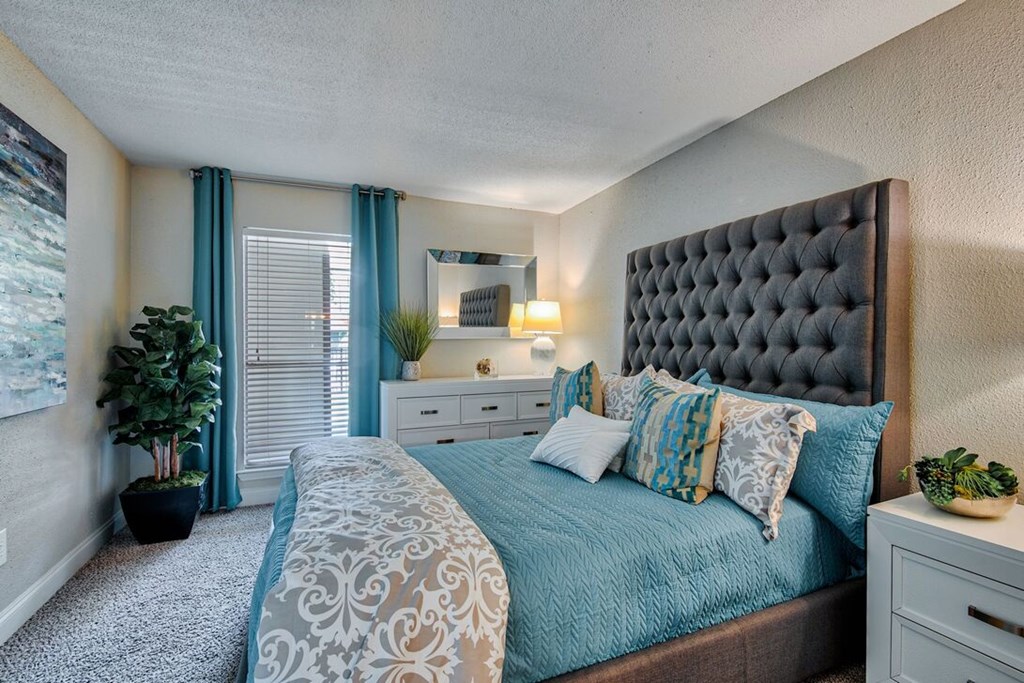 A bedroom with a large bed and a potted plant.