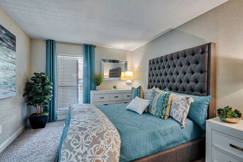 A bedroom with a large bed and a potted plant.