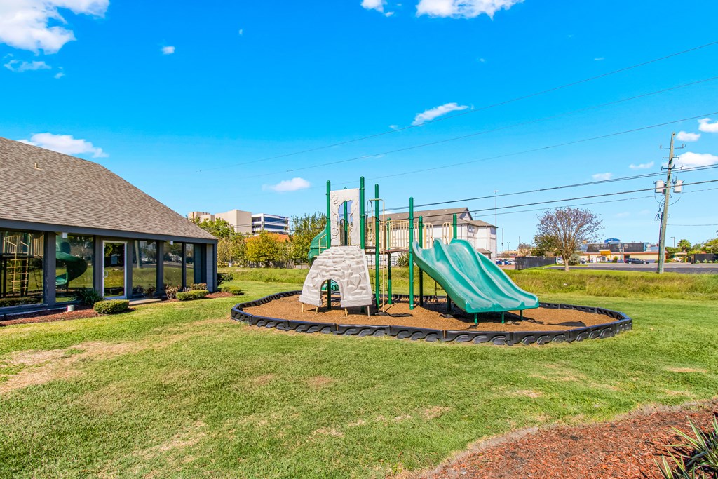 A playground with a green slide and a sandbox.