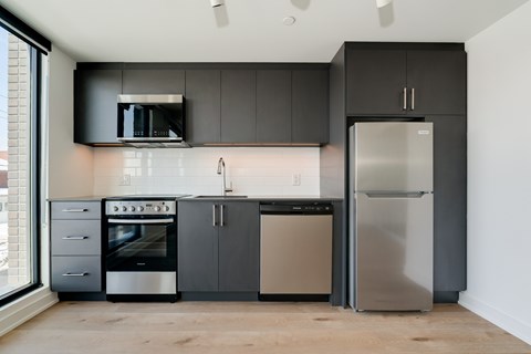 A modern kitchen with a stainless steel refrigerator and oven.