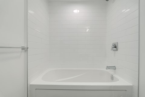 A white bathroom with a white tub and a white shower curtain.