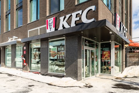 A KFC restaurant with a snowy sidewalk in front.