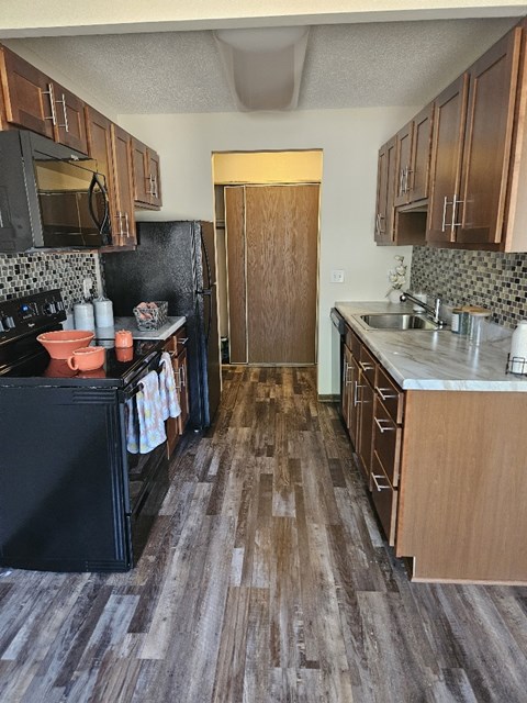 A kitchen with a black fridge, microwave, and oven.