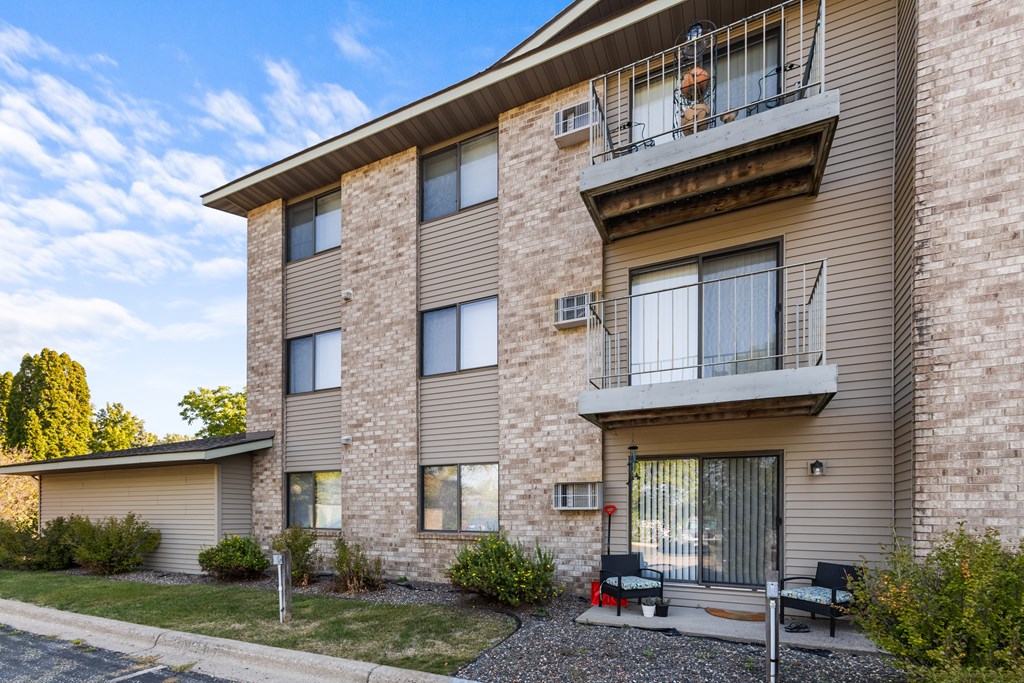 A residential building with a balcony and a small garden in front.