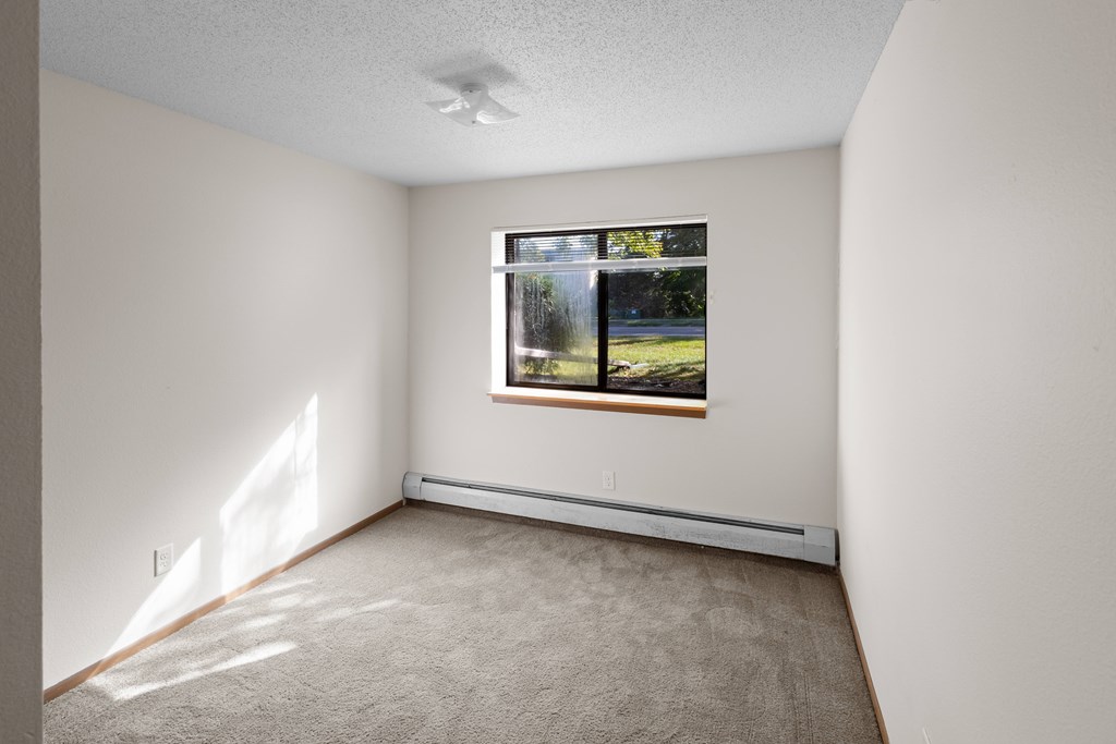 A room with a window showing a view of trees and a house.