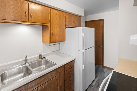 A kitchen with a white fridge and wooden cabinets.