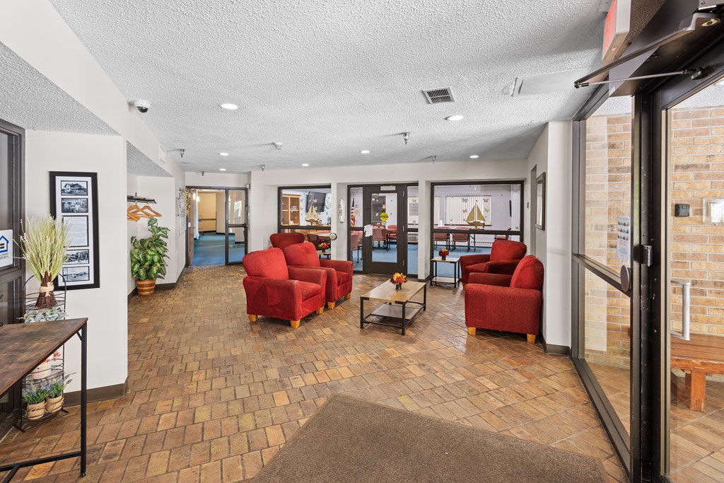 A room with red chairs and a brown rug.