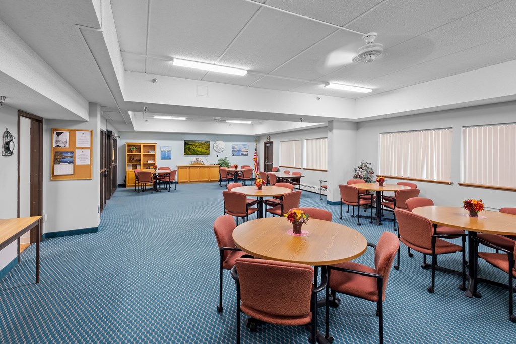 A room with tables and chairs and a blue carpet.