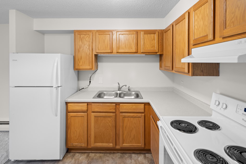 A kitchen with wooden cabinets and white appliances.