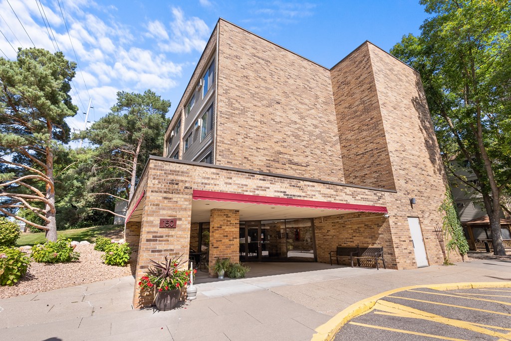 A building with a red awning and a sign that reads "The Pine Tree" is surrounded by trees and plants.