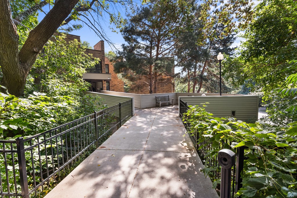 A walkway with a metal railing and trees on both sides.