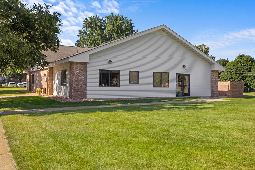 A white building with a brick chimney is surrounded by a grassy area.